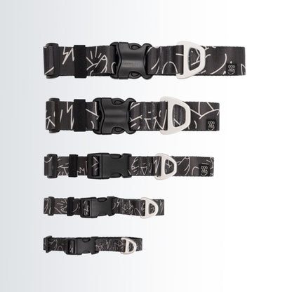 Five black dog collars with white abstract line patterns and silver metal D-rings, displayed in descending size order on a light gray gradient background.
