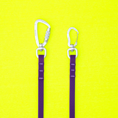 Two purple straps with silver carabiners on a yellow background