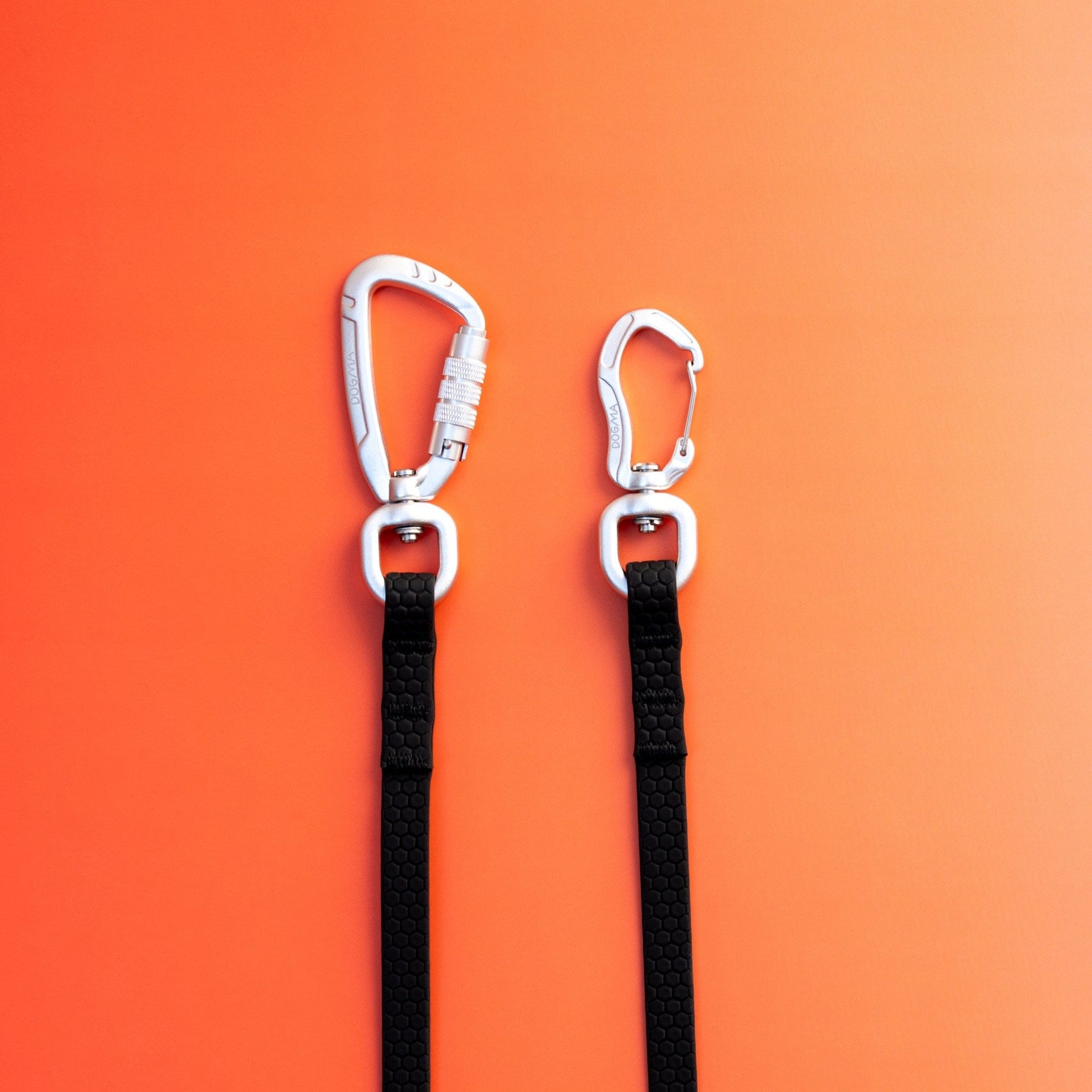 Two black straps with carabiners on an orange background